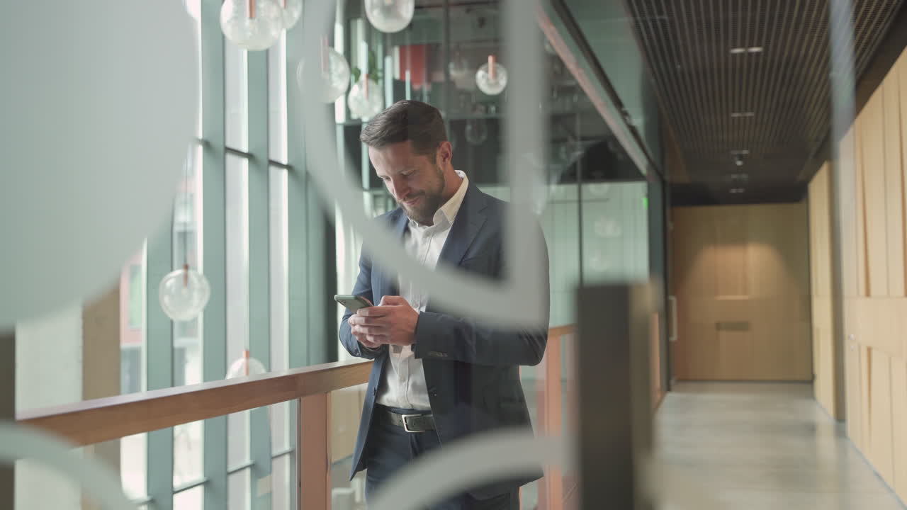 An Attractive Young, Bearded Businessman In A Blue Blazer Makes A Call With His Smart Phone