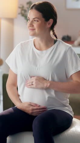 pregnant woman sitting on an exercise ball and smiling.