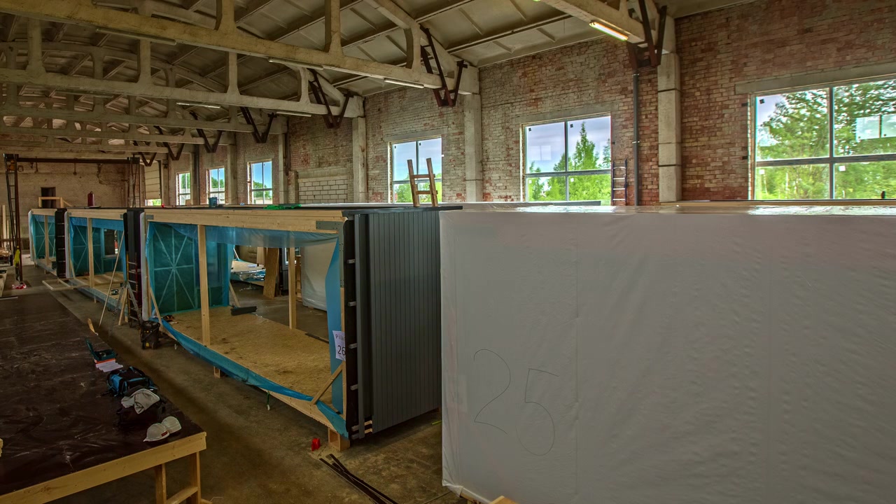 Falegnami all'interno di una fabbrica di costruzioni in legno che costruiscono case modello modulari, posizionando il legno e utilizzando attrezzi da falegname per costruire, riutilizzare e ristrutturare grandi container marittimi