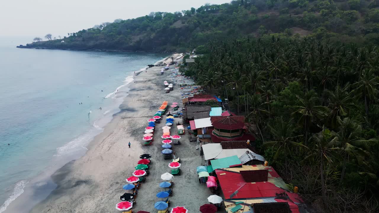 Calm and peaceful Virgin Beach in Bali with a cloudy sky, palm trees, gentle waves, and a tropical setting.