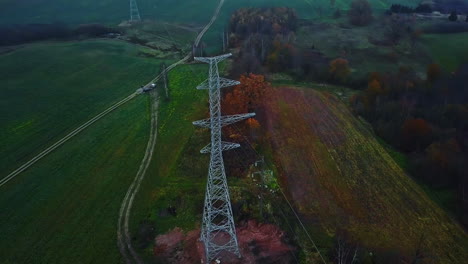 aerial view of new electric pylon tower in green countryside landscape on dark autumn day