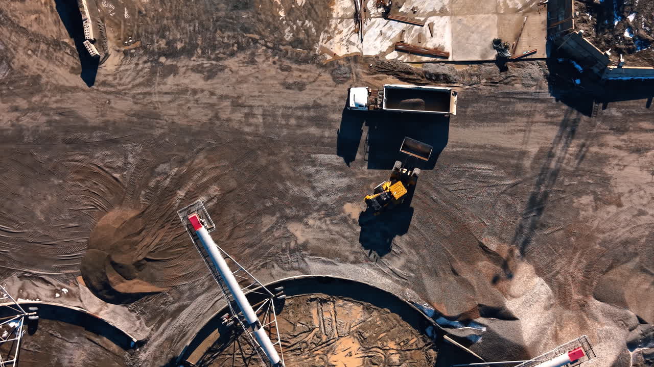 Top down view of loader loading truck at granite quarry. Aerial shot showing the process of stone loading into a heavy dump truck