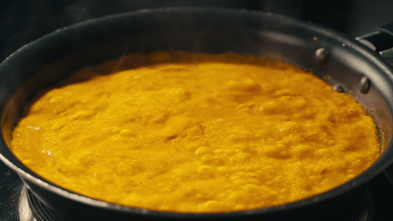 Yellow boiling sauce on pan close-up. Asian cuisine concept. Curry is a dish with a sauce seasoned with spices. Curries may contain fish, meat, poultry, or shellfish, either alone or in combination with vegetables. Others are vegetarian.