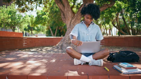 teenager holding laptop sitting in city park. girl working notebook