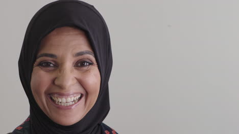 happy middle aged muslim woman laughing excited enjoying successful lifestyle wearing traditional hijab headscarf on blank background copy space close up