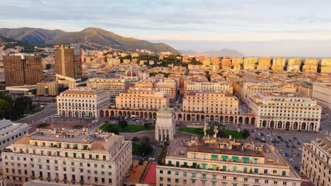 drone orbit over piazza della vittoria in genoa, showing symmetrical buildings and cityscape glowing in golden hour light