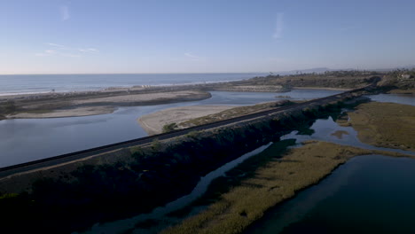amtrak train traveling along the southern california coastline by a lagoon and the ocean