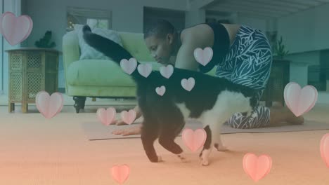 animation of pink hearts over black and white cat and biracial woman exercising in background