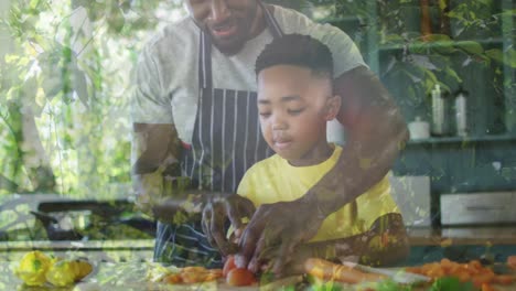animation of leaves over happy african american father and son cooking together