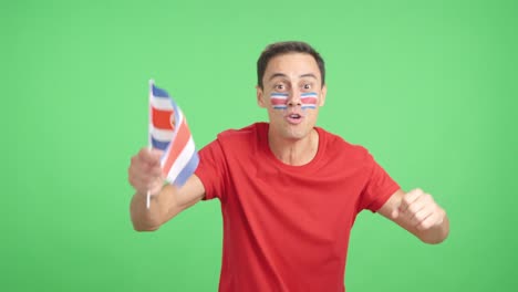 man cheering for costa rica screaming and waving a national flag