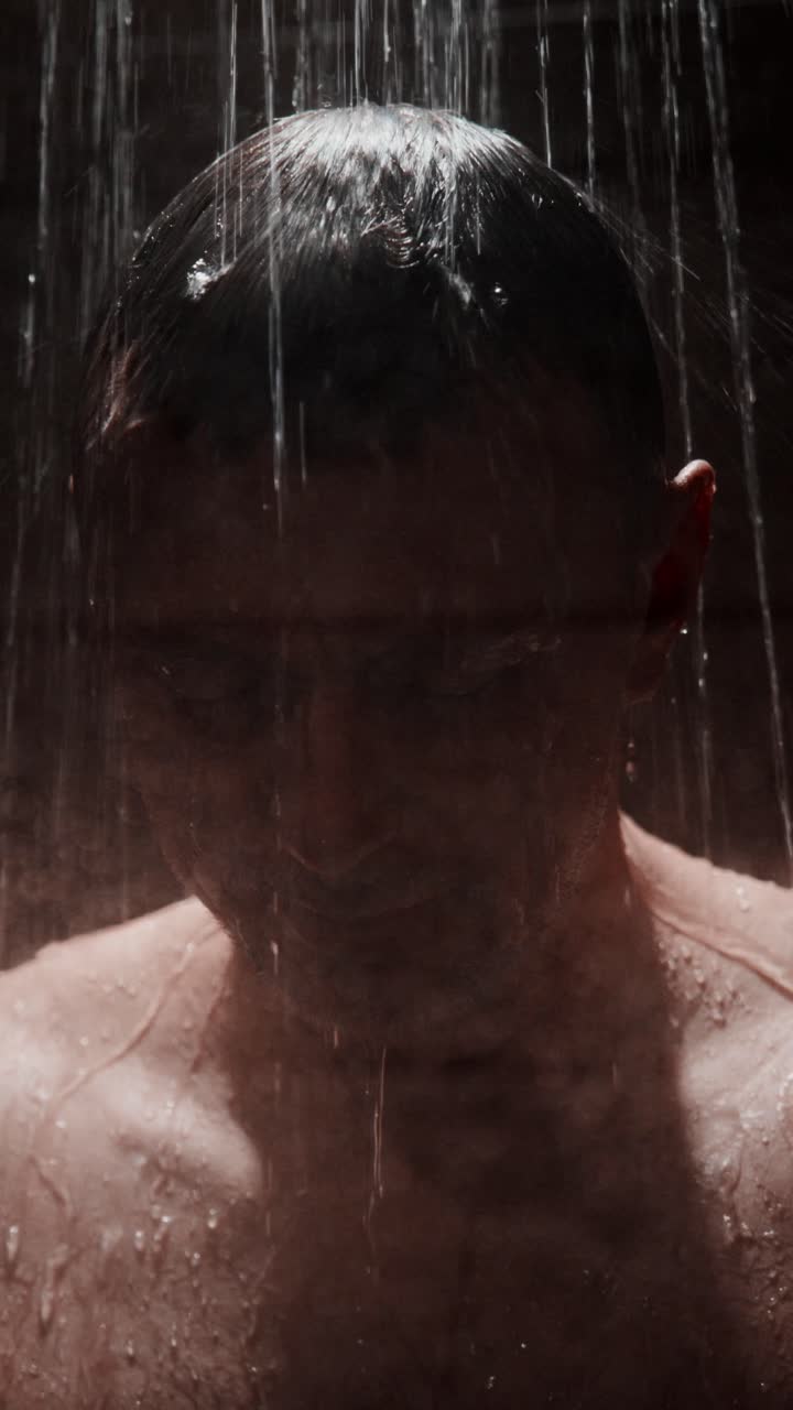 Man enjoying a rejuvenating shower experience in a dimly lit modern bathroom