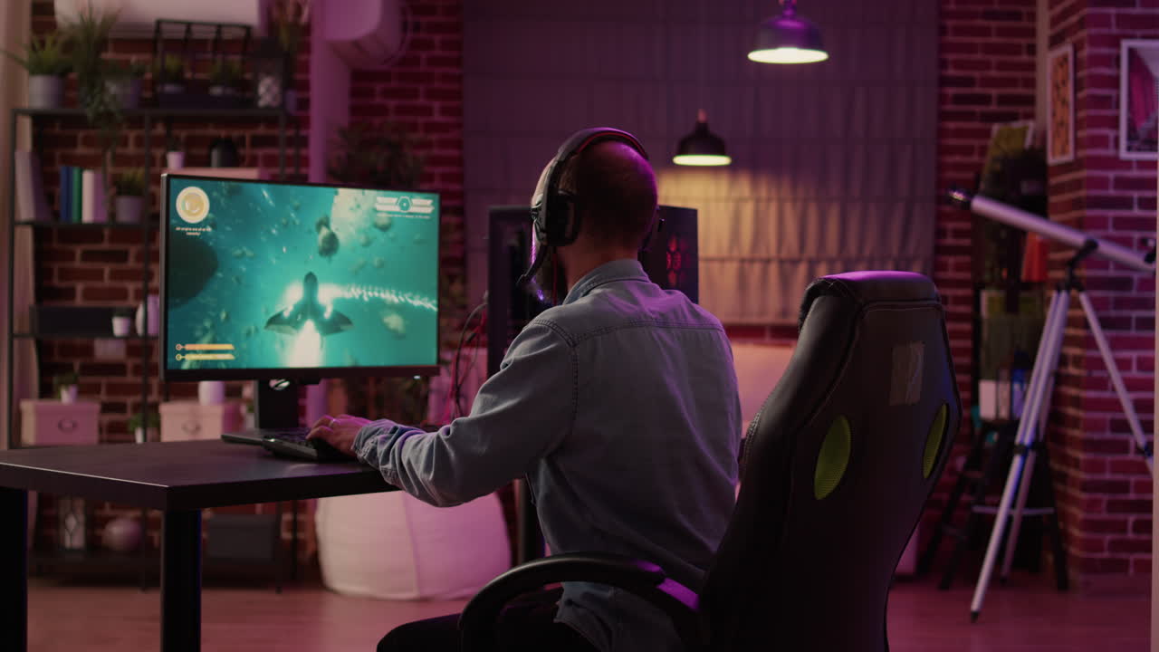 Over shoulder view of caucasian man using pc setup playing multiplayer online action game talking to team