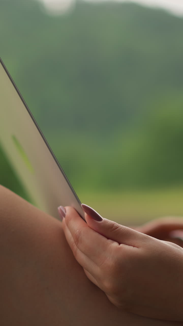 Donna naviga su internet con un moderno laptop, riposandosi su una terrazza aperta di un hotel eco-resort in montagna. Primo piano laterale, rallentato.
