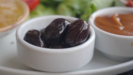 aceitunas negras en un pequeño cuenco blanco con salsa