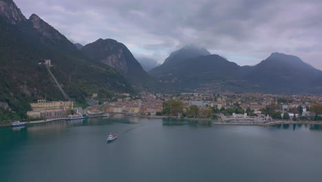 Static-aerial-shot-of-large-passenger-boat-pulling-out-of-the-Riva-Del-Garda-port,-Italy