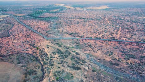 aerial drone shot of a dried up river bed and semi arid forest with a village road of gwalior in madhya pradesh india