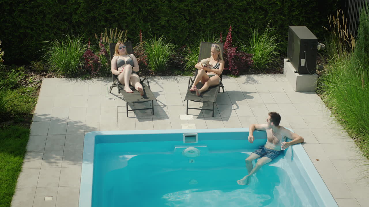 En mand med en cocktail slapper af i poolen ved siden af to smukke kvinder. Drømmeferie.