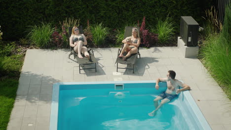 a man with a cocktail is relaxing in the pool, next to two beautiful women. dream vacation