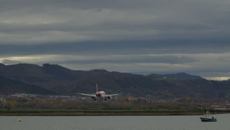 airplane landing over coastal mountains and calm water