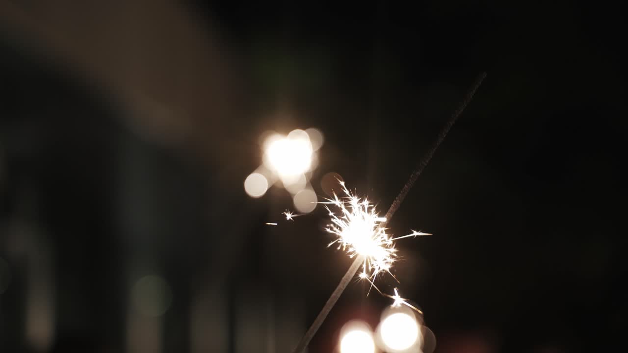lit sparkler glowing against a dark background with soft bokeh lights