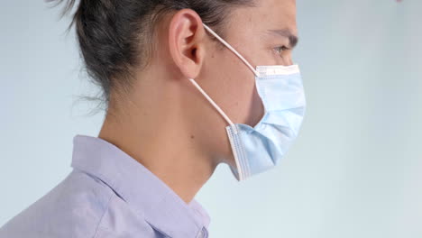 Joven-Con-El-Pelo-Largo-Poniéndose-Una-Máscara-Médica---Foto-De-Perfil