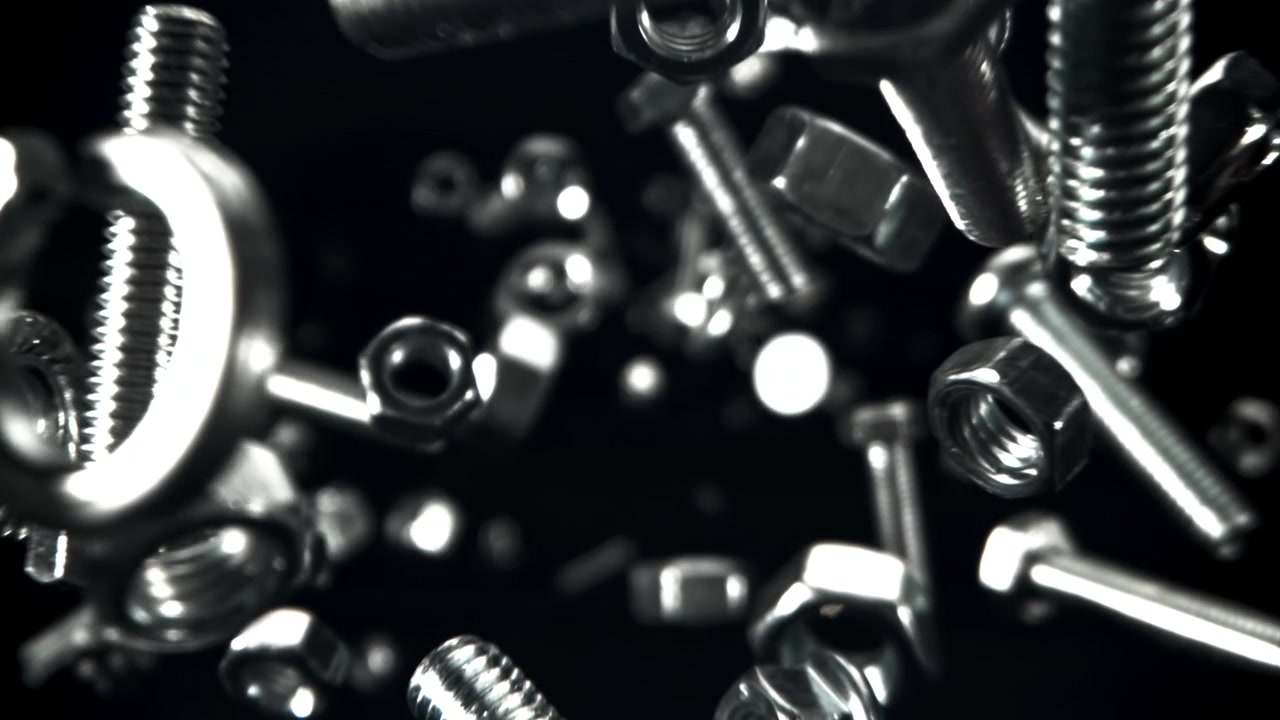 Elementi di fissaggio metallici lucidi che cadono su uno sfondo nero