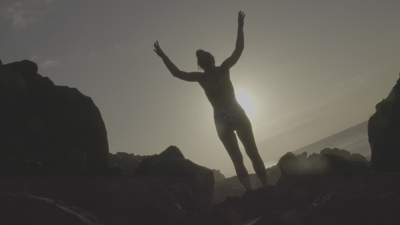 Woman on a rocky beach at sunset