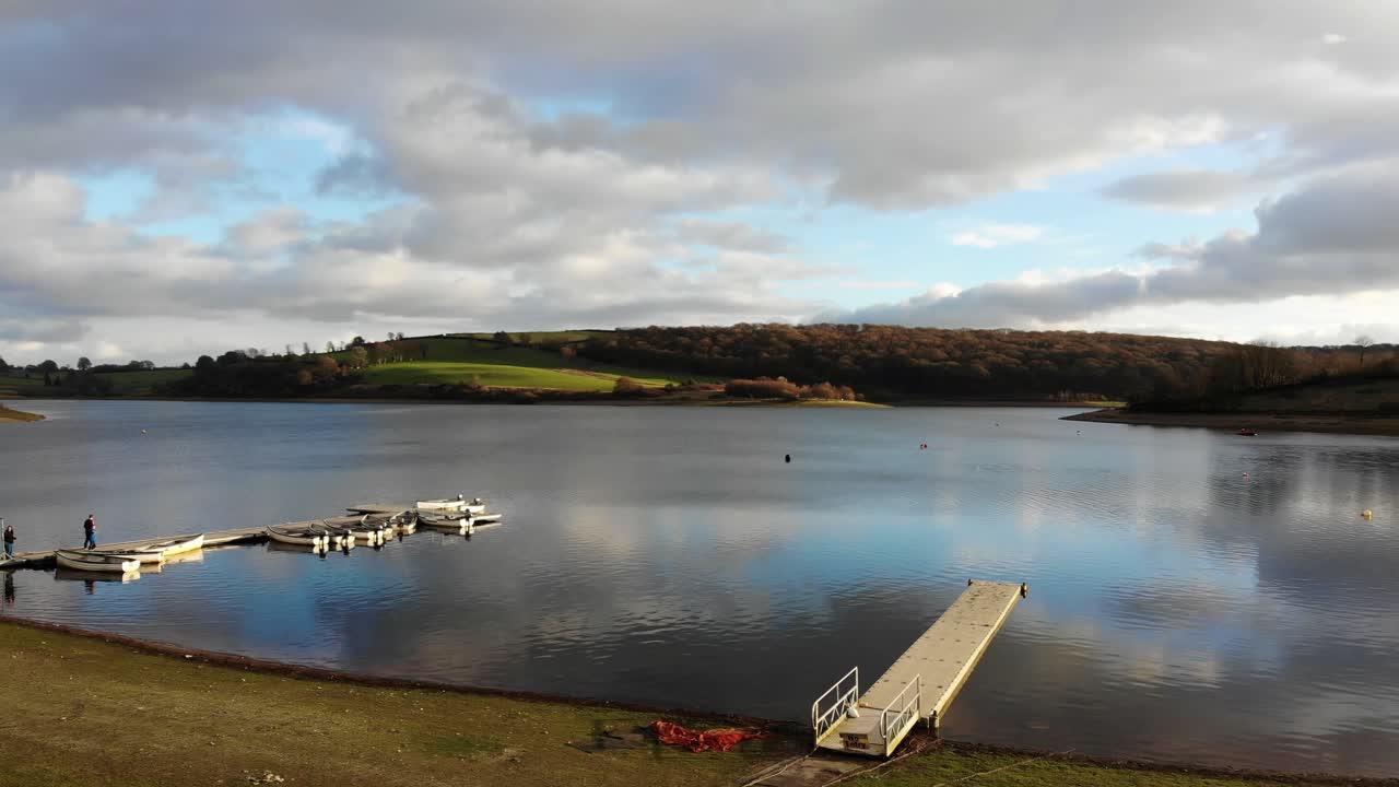 antena volando sobre la playa hacia el muelle con botes vacíos amarrados en el lago wimbleball en exmoor en somerset