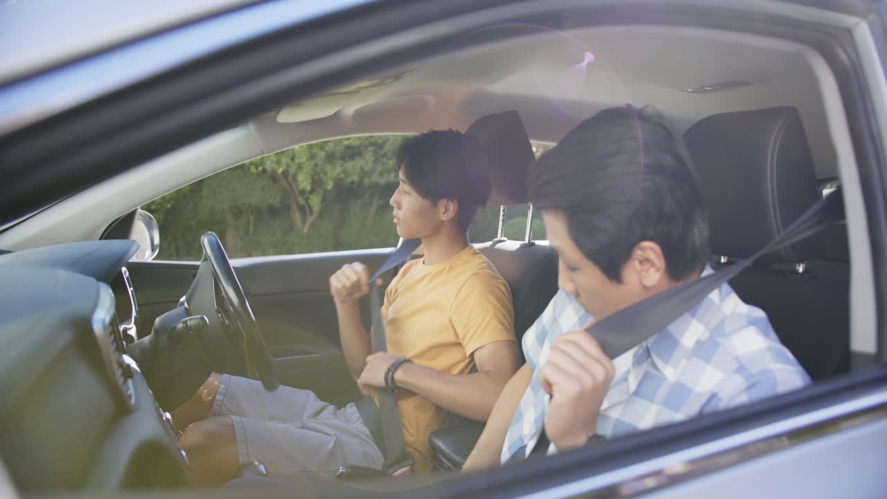Learning to drive, young asian man receiving directions from instructor in car