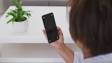 mujer mayor afroamericana sentada en el sofá usando un teléfono inteligente, con espacio de copia en la pantalla