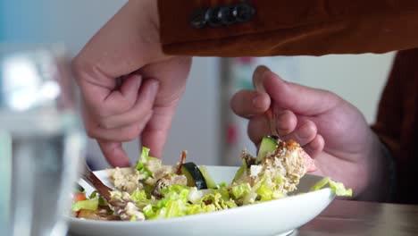 man in suit eating a healthy salad vegetable meal at the restaurant rearranges food with his fingers