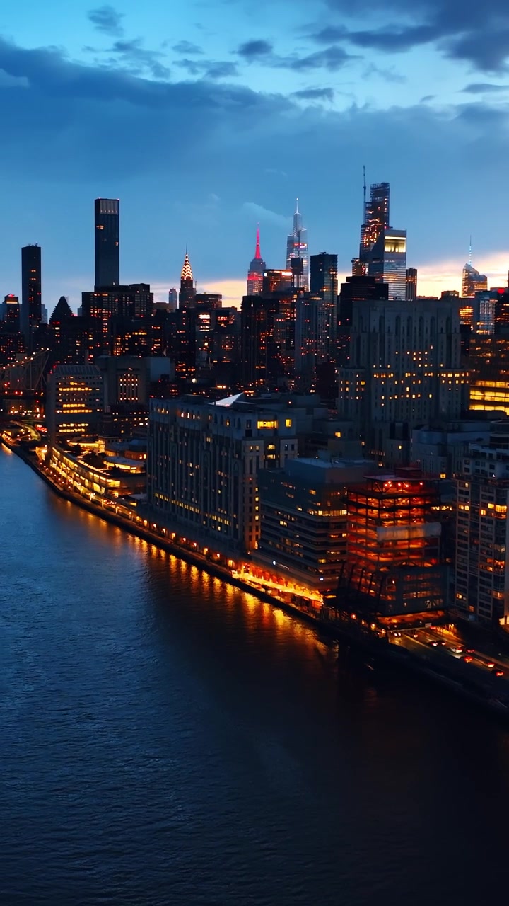 Riprese con drone sopra il fiume a New York di notte. Bella architettura moderna della città con un'illuminazione straordinaria. Video verticale.