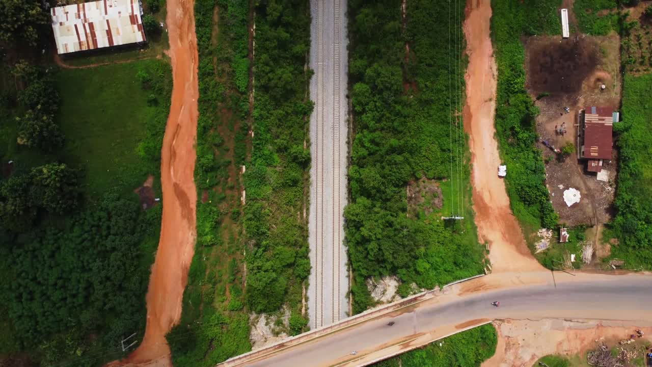 Top down aerial of a long traintrack running through a rustic area in Nigeria, Africa on a sunny day