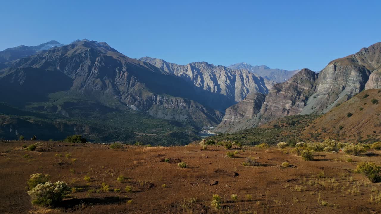 Svelamento ascendente di una valle arida con lo sfondo di un'imponente catena montuosa.