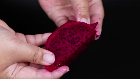 hands peeling and examining dragon fruit slice