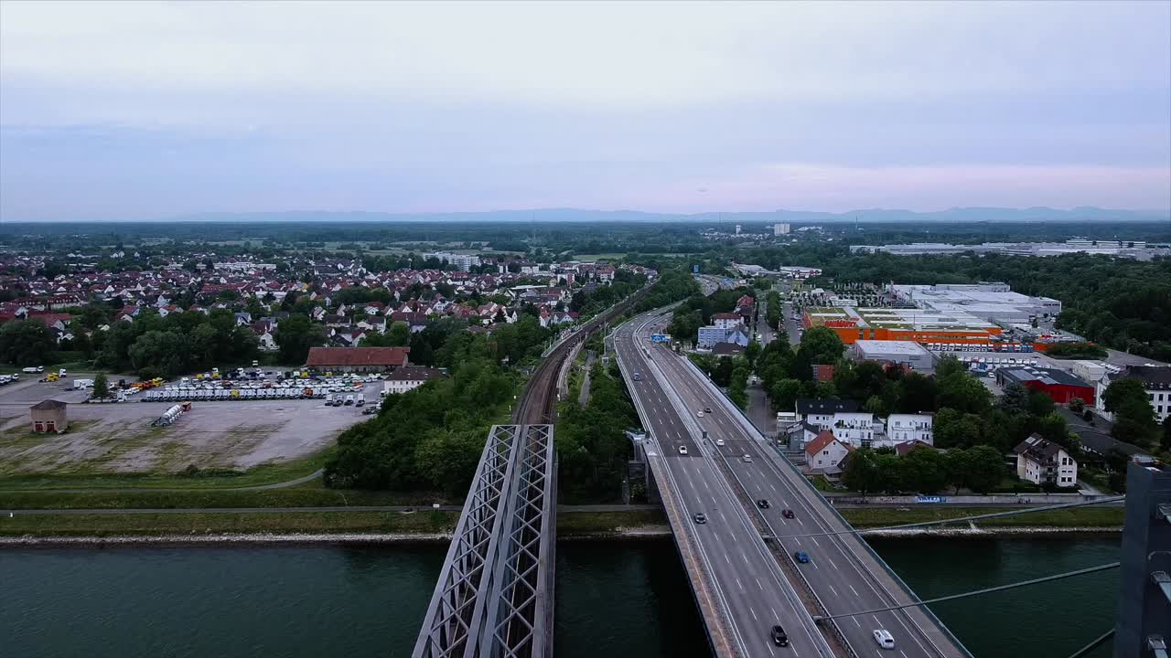 Aerial footage of a drone flying backwards over a River in Europe with a beautiful bridge next to a railroad track