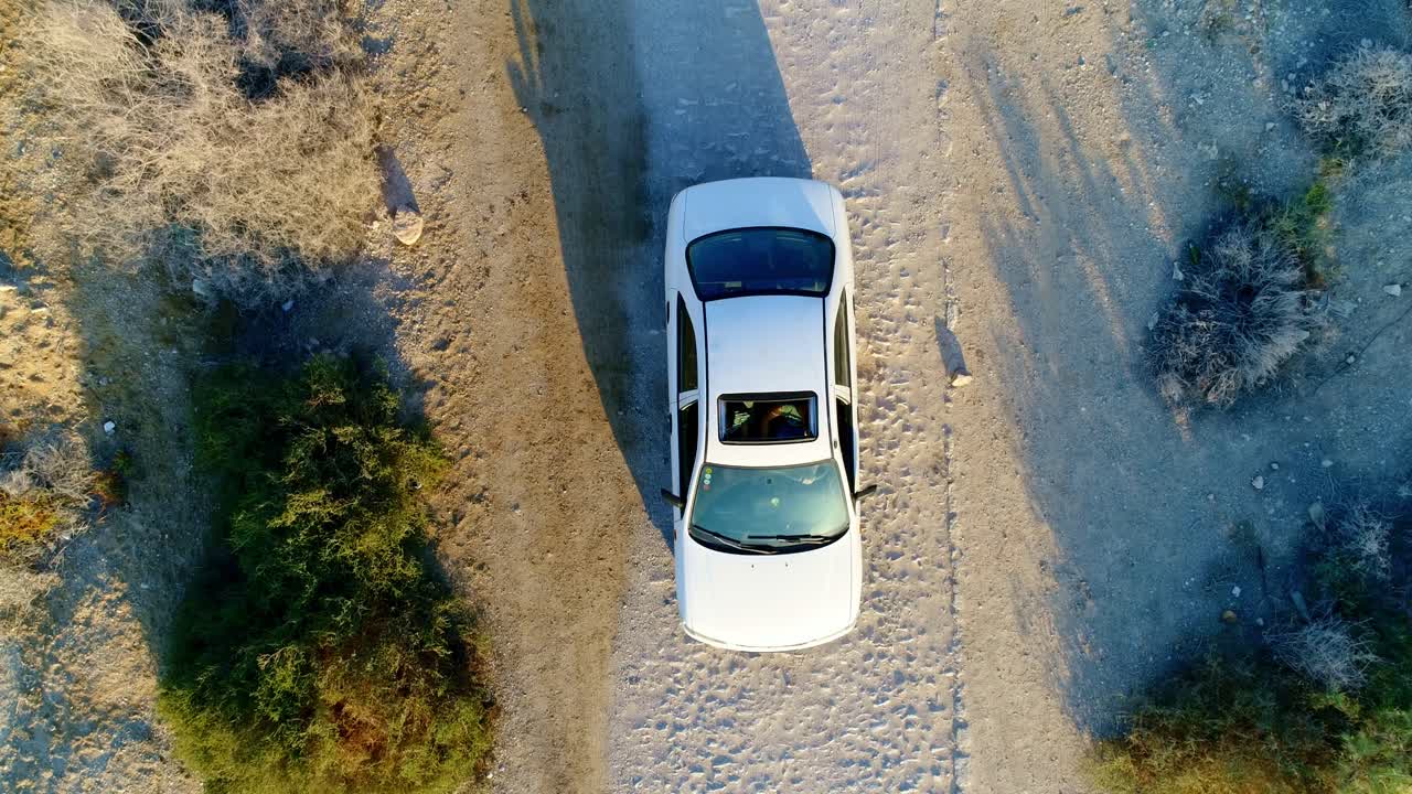 Ripresa dall'alto con drone di un'auto che si ferma su una strada sterrata