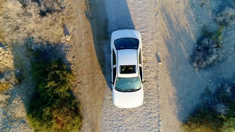 toma superior de un dron de un auto que se detiene en un camino de ripio