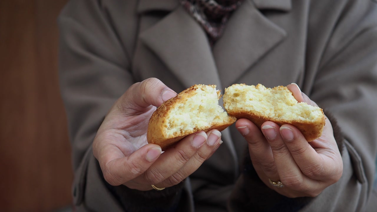Close-Up of Hands Breaking a Freshly Baked Pastry