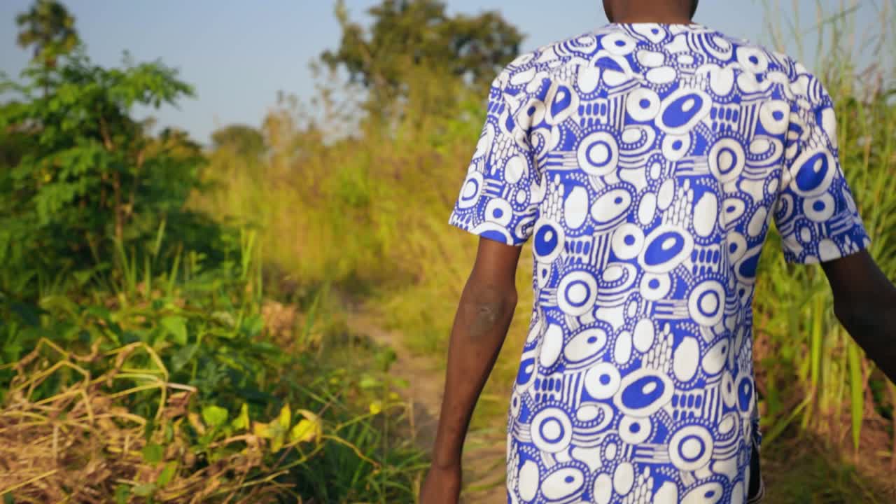 African Boy Walking Through a Field