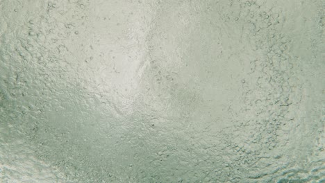 top view of underwater deep blue ocean during raining seeing ripple and wave water with bubble moving on surface with sunlight. it is beautiful pattern and texture for background.