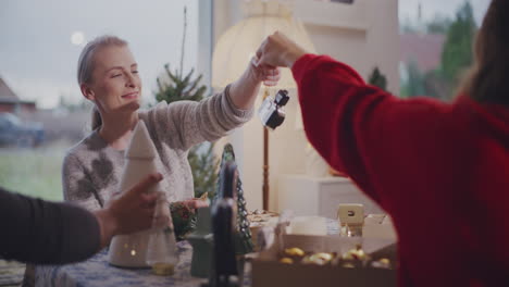 woman giving camera to female friend at home