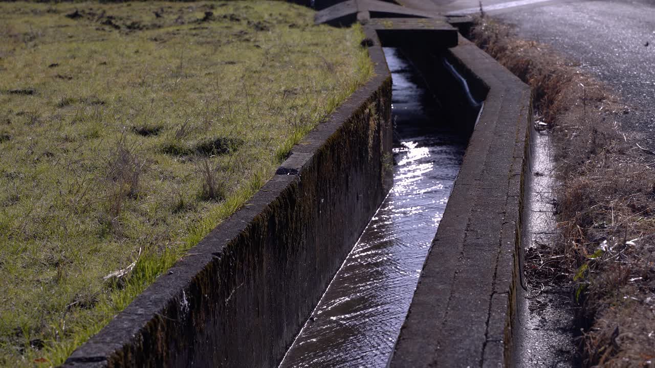 pequeño río de riego que corre junto al campo de hierba en un entorno rural