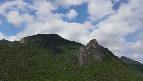 imágenes aéreas ascendentes tomadas desde la distancia que revelan hermosas nubes blancas esponjosas, cielo azul y las montañas