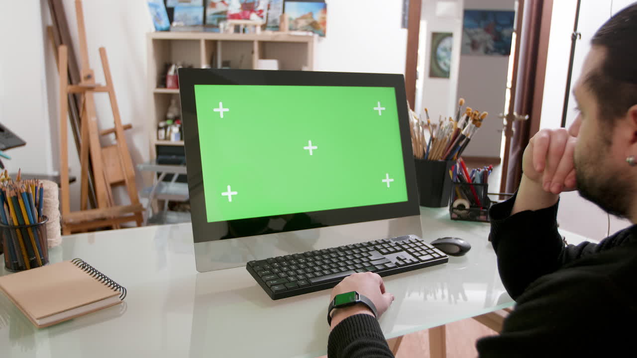 Man Using Computer with Green Screen in Art Studio