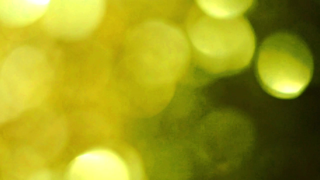 Abstrakte gelbe und grüne Bokeh-Lichtpartikel auf schwarzem Hintergrund