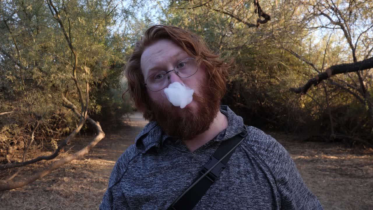 hombre pelirrojo mostrando su vape y fumando