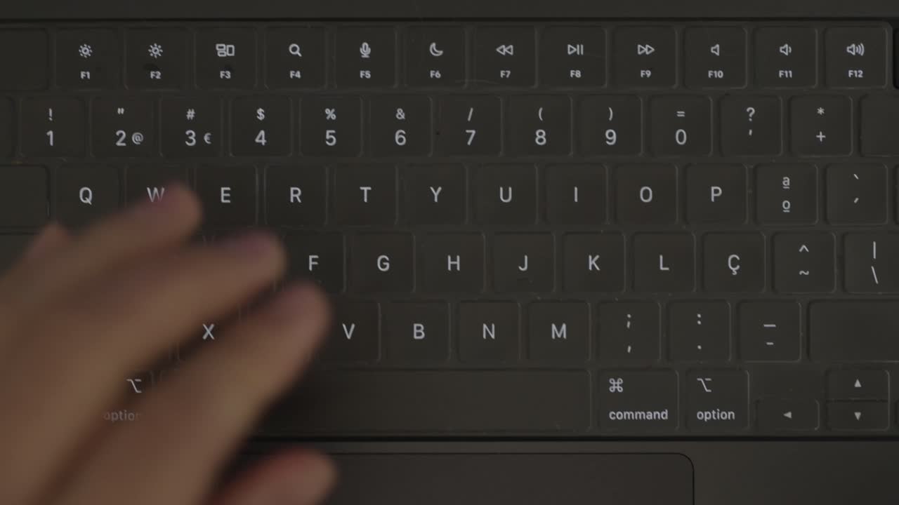 Close up of person typing on laptop keyboard working on computer indoors