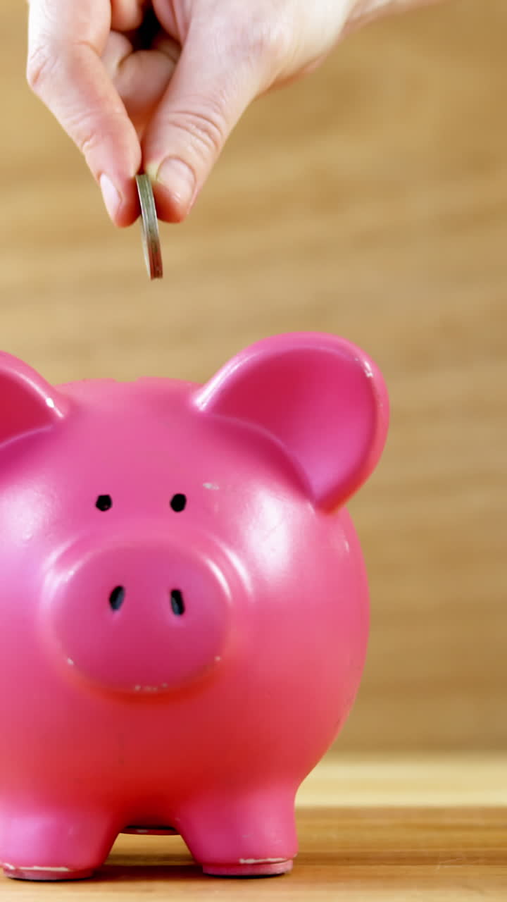 la mano dejando caer la moneda en la alcancía