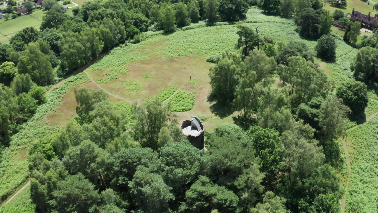 съемка с воздуха вокруг старинной башни-фолианта в английской сельской местности с сохранением фолианта в кадре